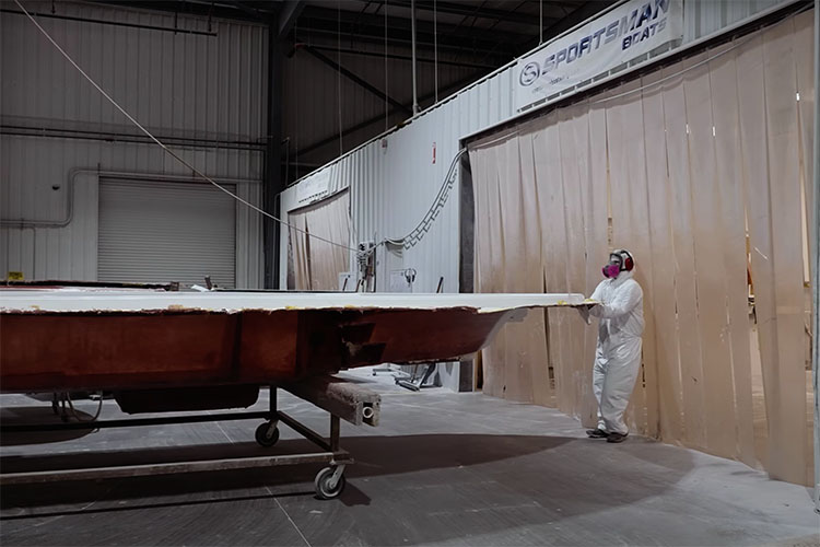 Image of a Sportsman Boats employee, wearing full ppe, pulling an unfinished boat deck into the cut and grind room.