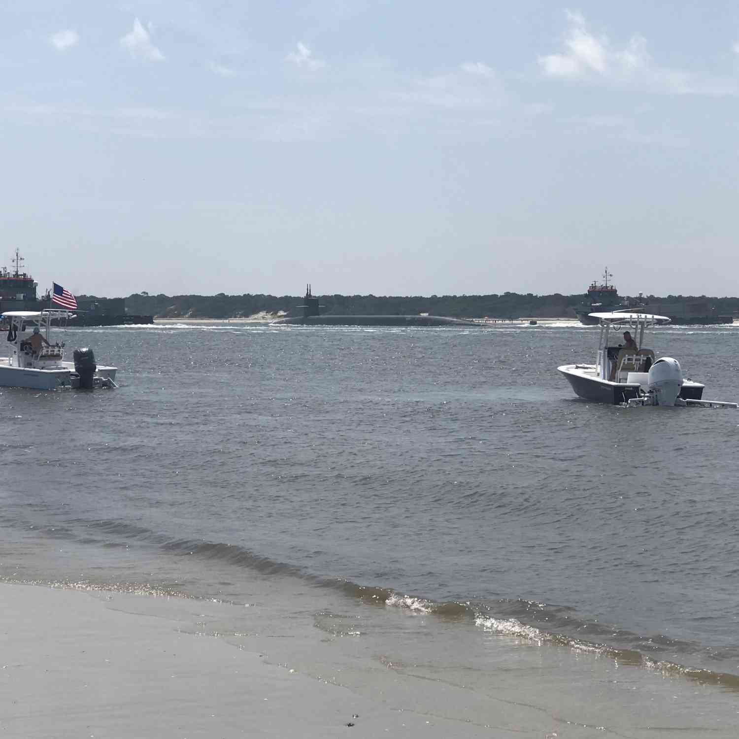 Two boats. One American flag and a US Navy Submarine headed out to sea